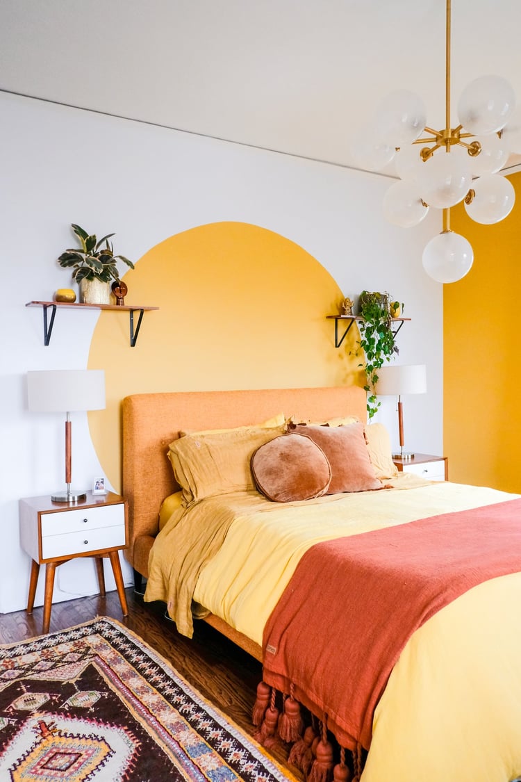 yellow orange blush and red bedroom design with indoor greenery and paint feature