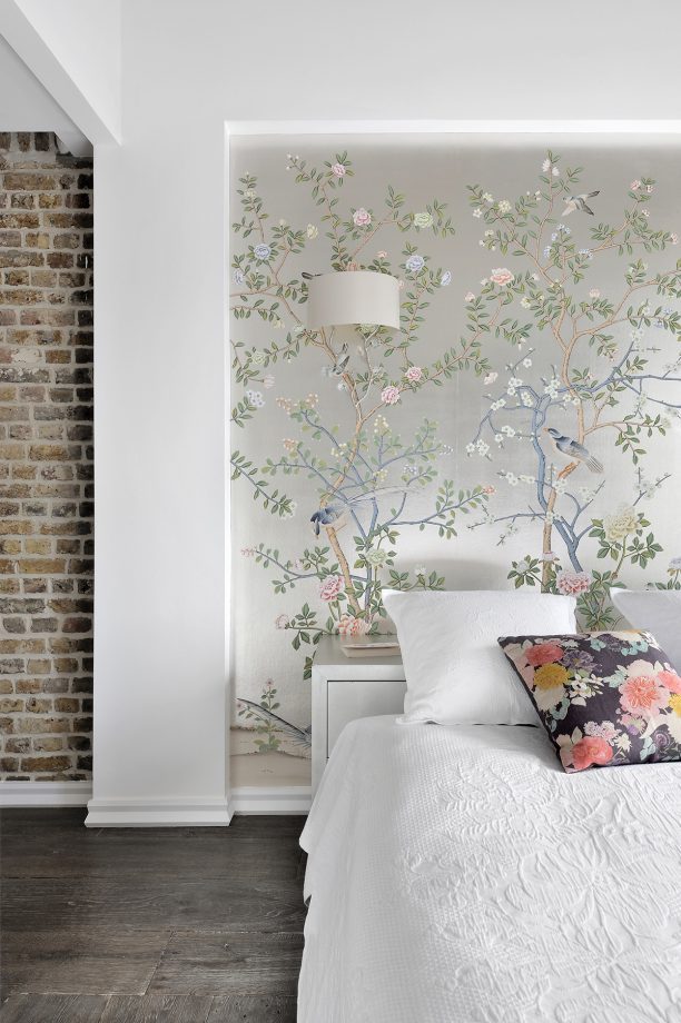 bedroom with floral feature wall paper exposed brick wall and decorative cushions and wall lights