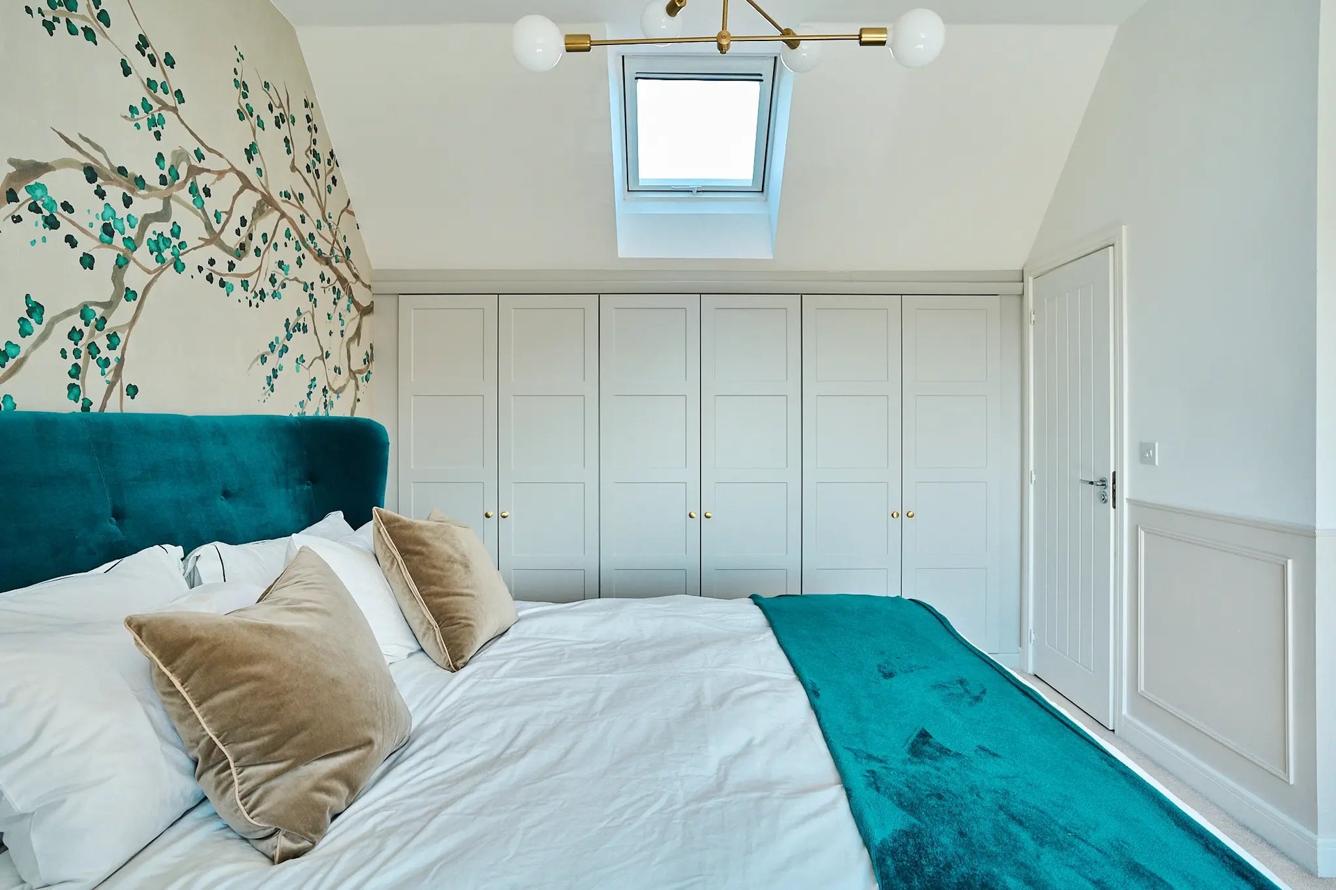 Bright, light loft bedroom with bold teal bed