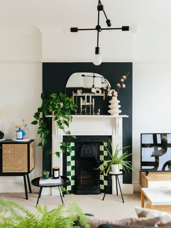 Fireplace with green tiles, black wall and plants