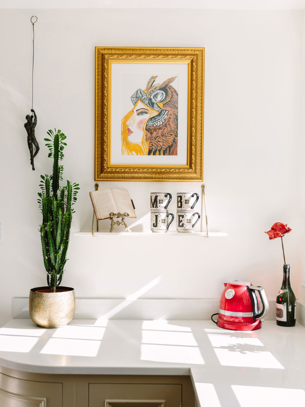 white wall with painting, cactus plant and hanging decoration