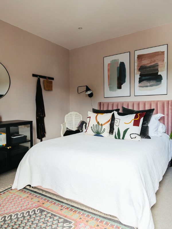pink bedroom with art and patterned pillows