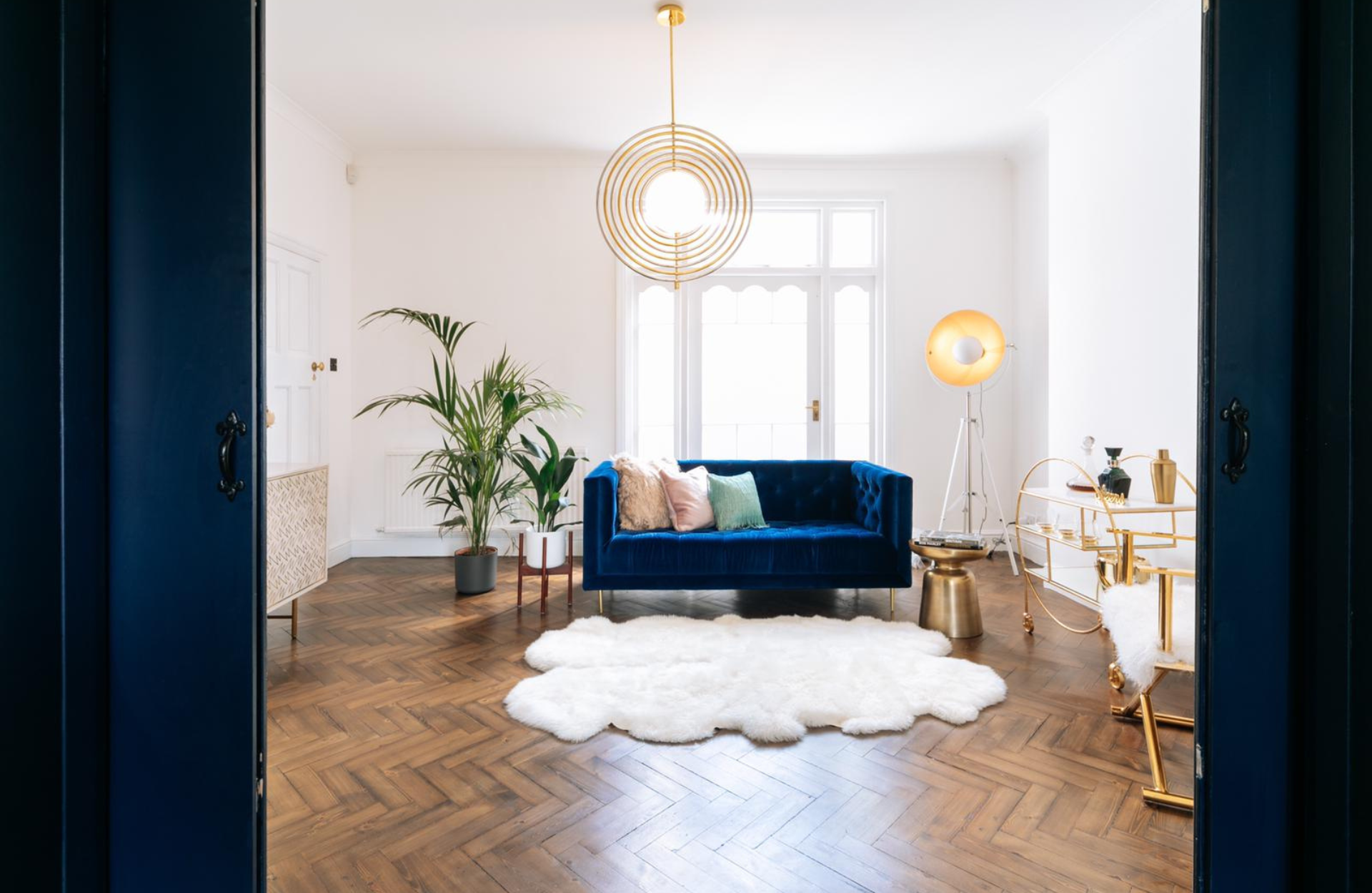 white living room with blue sofa and gold accessories