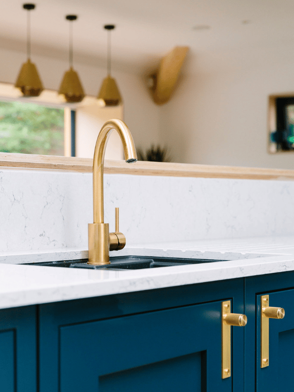Sink with blue kitchen cabinets, gold taps and handles